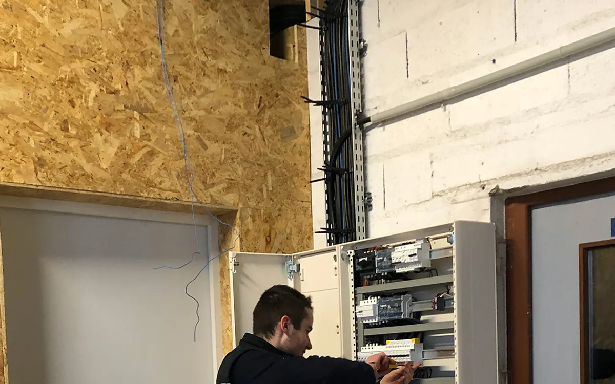 Technicien Bourdeix en plein cablage d'une armoire electrique industrielle, disjoncteurs et automates alignes