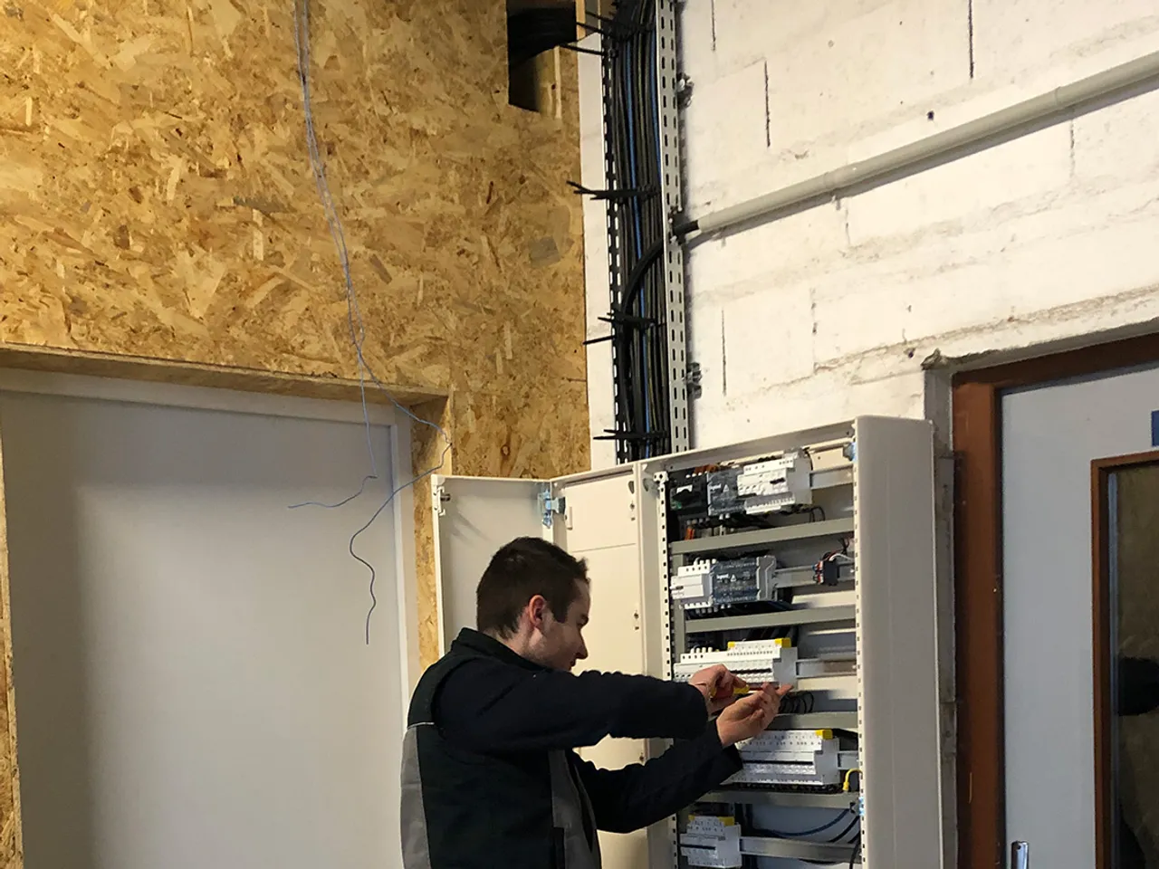 Technicien Bourdeix en plein cablage d'une armoire electrique industrielle, disjoncteurs et automates alignes